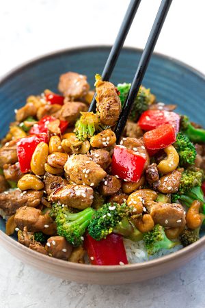 Healthy Cashew Chicken - an easy 20 minute guilt-free gluten free skinny version (plus paleo friendly options) of the popular classic Chinese takeout dish. Plus a serving of tender crisp broccoli and red bell peppers for a healthier meal. Best of all, this recipe comes together in less than 30 minutes in just one pan and perfect for busy weeknights!