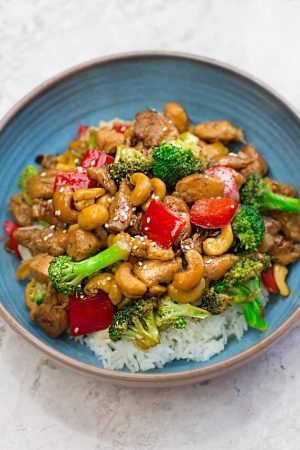 Healthy Cashew Chicken - an easy 20 minute guilt-free gluten free skinny version (plus paleo friendly options) of the popular classic Chinese takeout dish. Plus a serving of tender crisp broccoli and red bell peppers for a healthier meal. Best of all, this recipe comes together in less than 30 minutes in just one pan and perfect for busy weeknights!