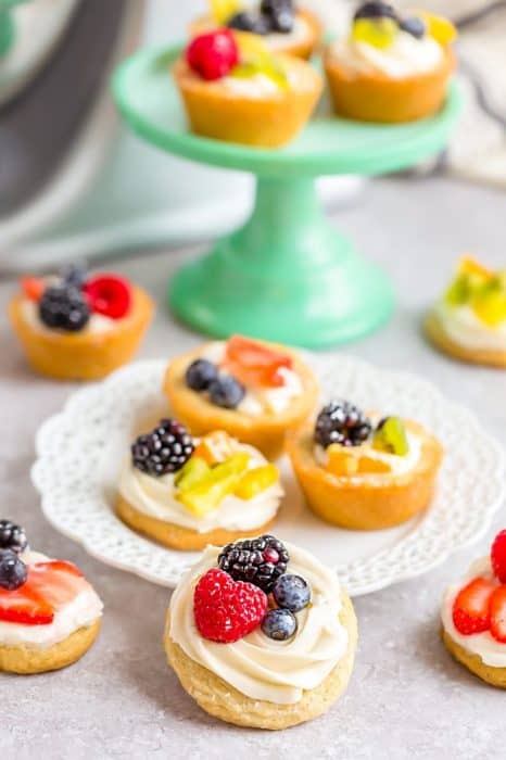 Mini Fruit Pizza - a classic dessert made using homemade soft sugar cookies topped with fresh fruit. Perfect for spring or summer barbecues, potlucks, showers, and parties. Best of all, no dough chilling required and easy to customize! Use a mix of fresh strawberries, blueberries, blackberries, raspberries, kiwi, mandarin oranges or pineapples!