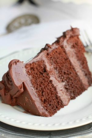 Ultimate Triple Chocolate Layer Cake - The best triple layer chocolate cake with the easiest milk chocolate frosting covered with mini chocolate chips.